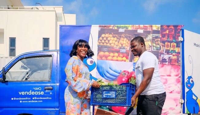 2 people holding crate of food in front of Vendease delivery van