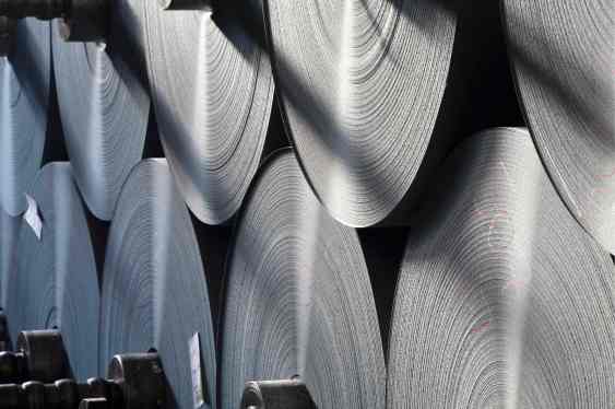 Large rolls of fresh paper sit stacked in a warehouse.