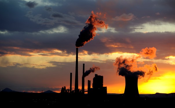 Coal power station with smoking chimneys at sunset against a cloudy sky.